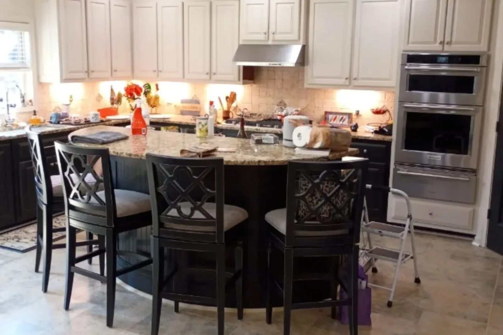 Two-tone kitchen with cream upper cabinets and dark island after cabinet painting