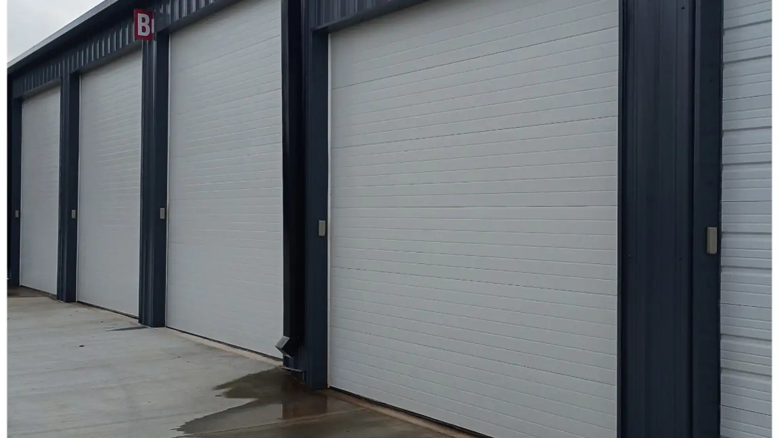 Commercial roll-up doors freshly painted with dark metal trim, from a Wheeler Painting commercial project