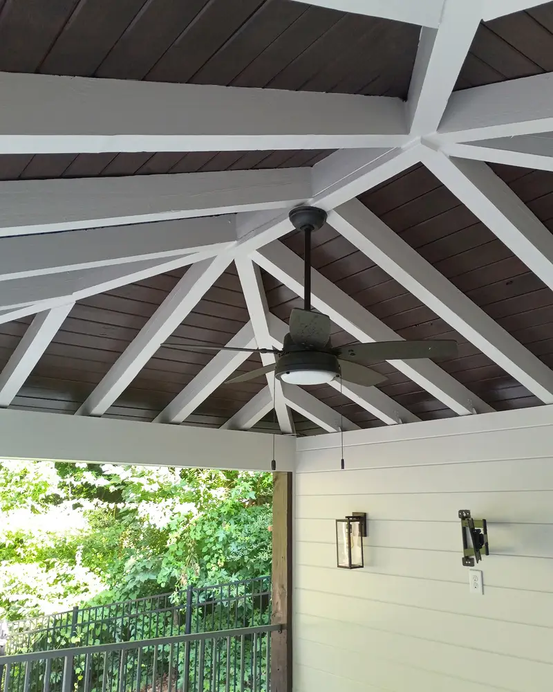 Covered porch with white painted beams and a stained ceiling, from a Wheeler Painting project