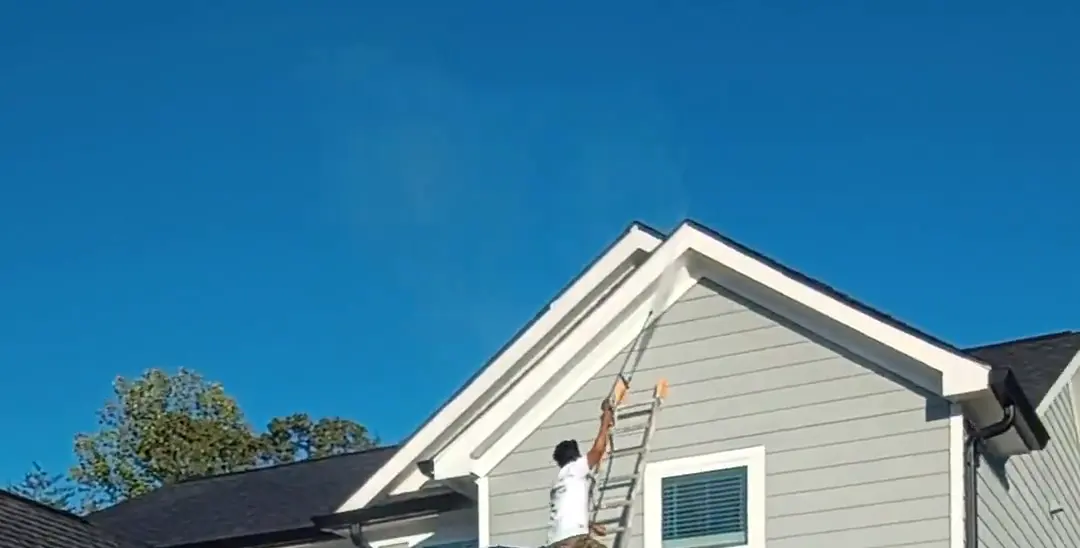 Wheeler Painting crew member on a ladder painting the gable of a Magnolia Station home in Lula during a full exterior repaint