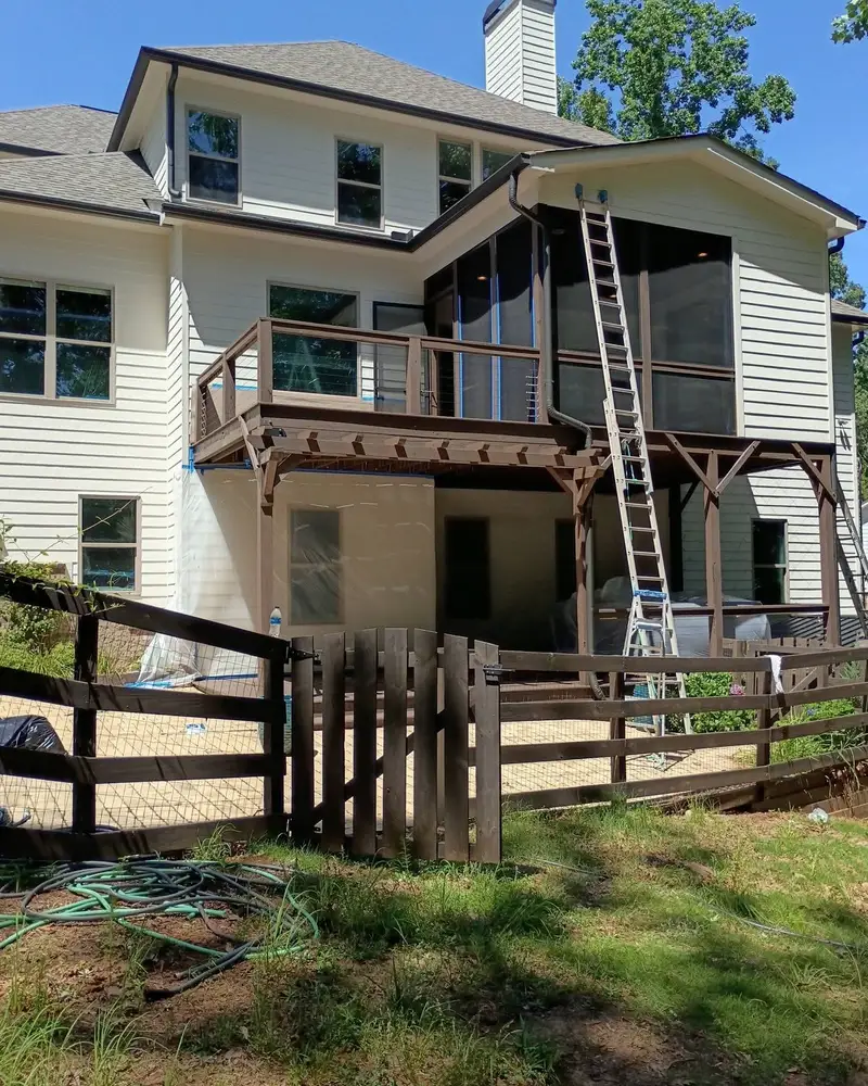 Rear of a two-story home with a deck and ladder set up, from a Wheeler Painting exterior project