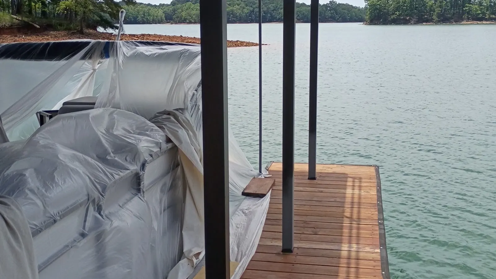 Stained lake dock and boathouse with a covered boat on Lake Lanier